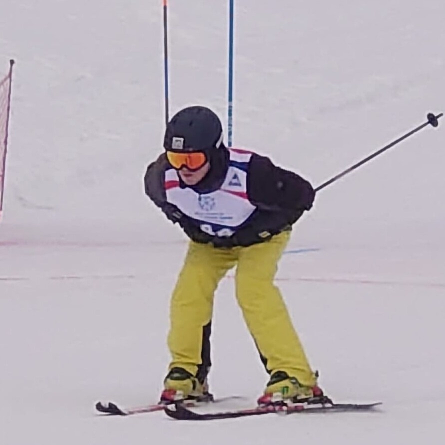 Background is complete snow, Richard is on is skis leaning forward and gliding through the snow